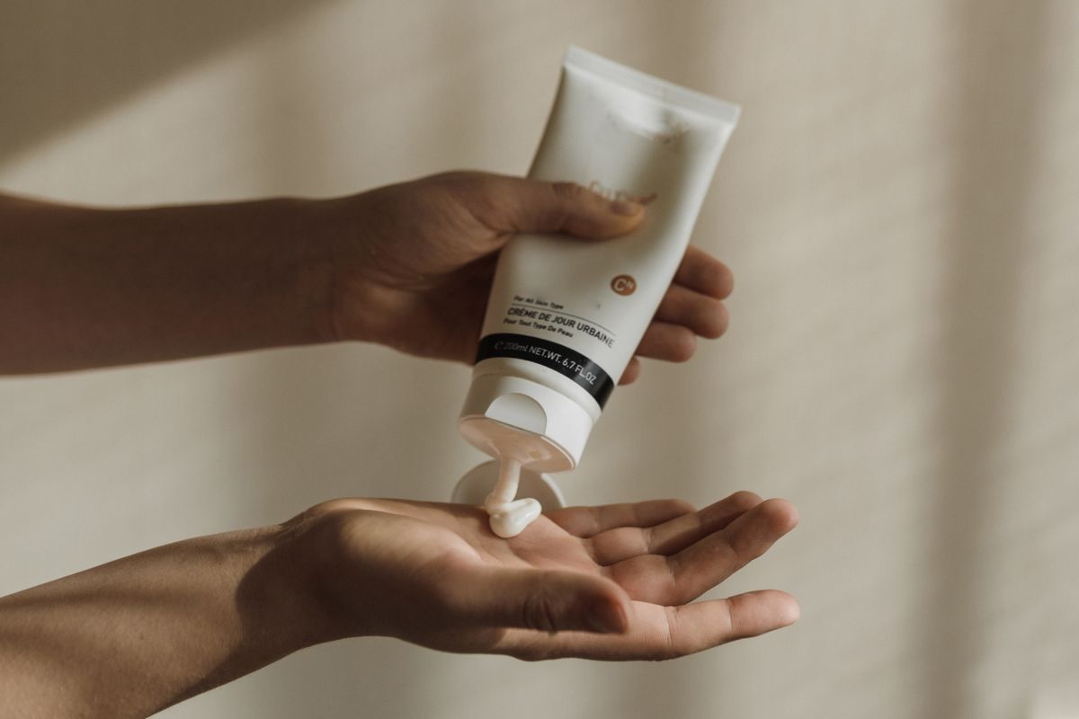 Uncapped lotion tube beside folded towels on a bathroom counter