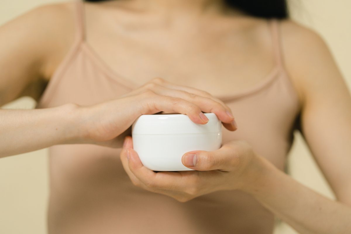 Open jar of white moisturizer cream with smooth texture on a countertop