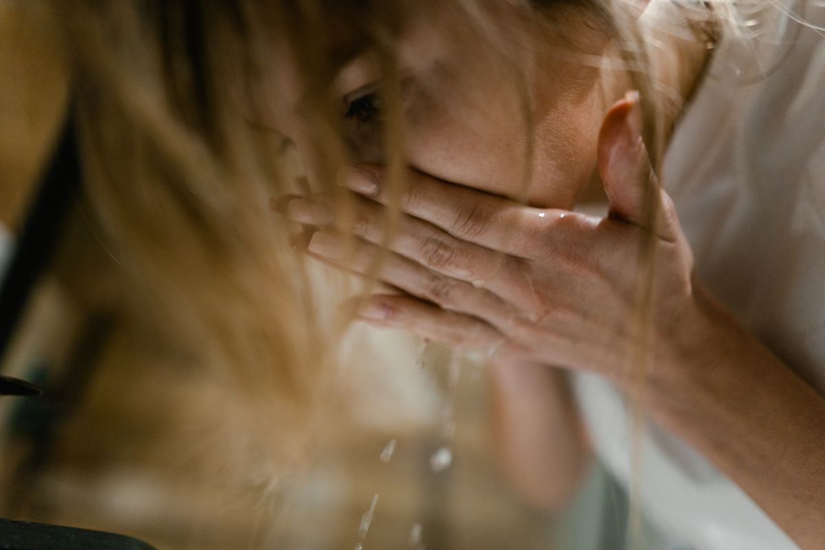 Woman washing her face with a gentle cleanser at the sink