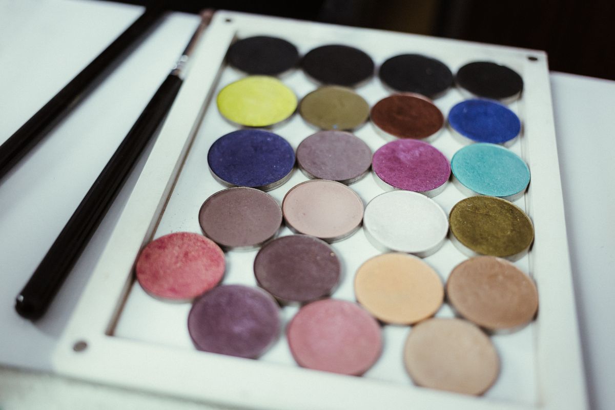 An open eyeshadow palette beside brushes and a small powder puff