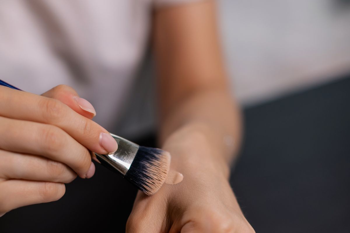 A person testing foundation shades on the back of a hand
