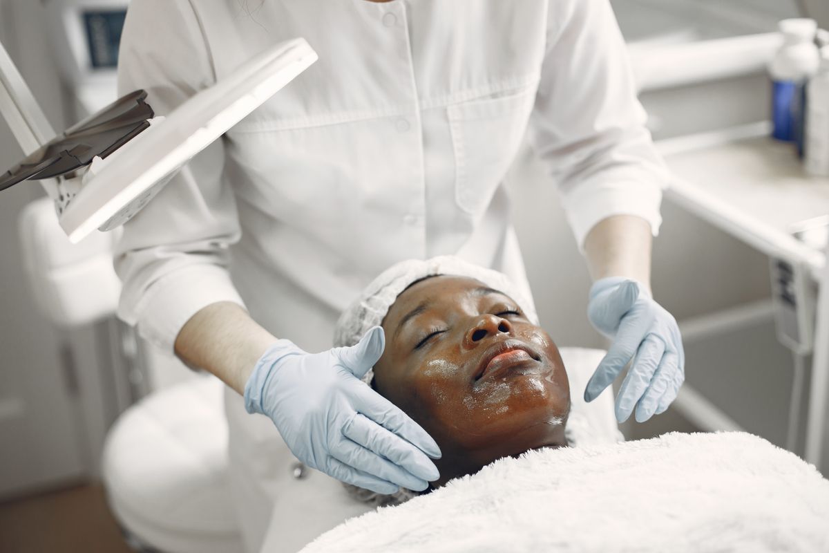Woman applying moisturizer to her neck in a bright bathroom mirror