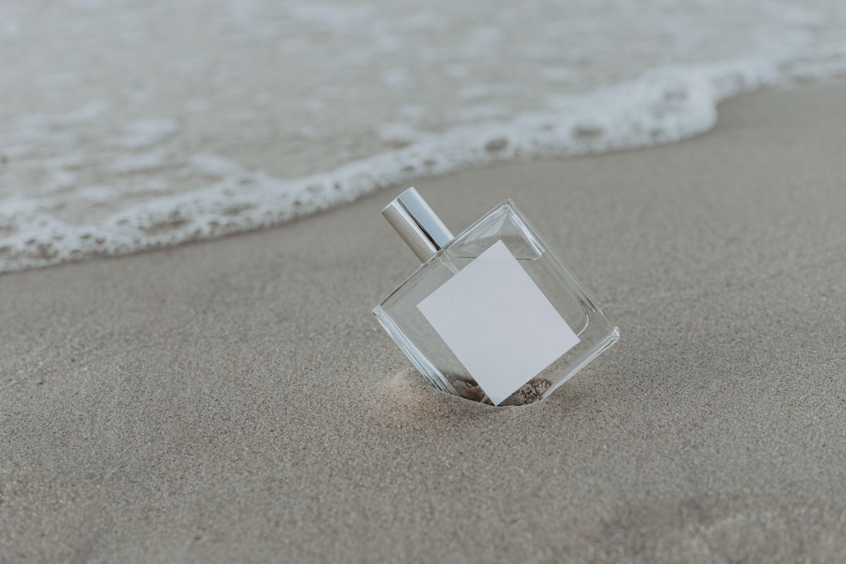 A perfume bottle standing on sand in warm evening light