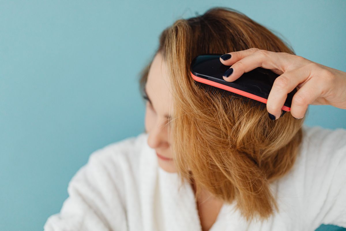 A woman brushing her hair with a paddle brush